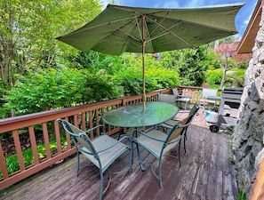 Deck has a dining table and propane grill