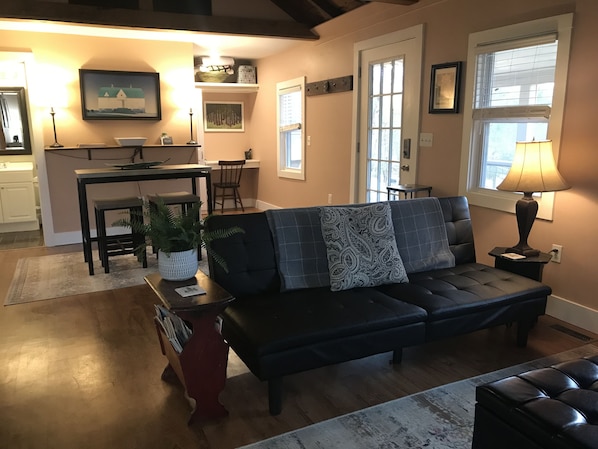 Living room with full size futon, TV with DVD player, ceiling fan, exposed wood