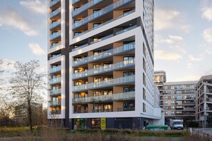 A modern residential building with a sleek and elegant facade surrounded by greenery.
