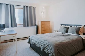 Spacious master bedroom with a queen-sized bed. Includes a desk and computer monitor for working remotely