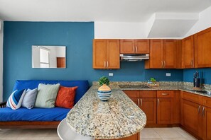 Inside a well-lit apartment, the living area flows seamlessly into an open kitchen.