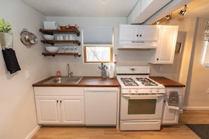 Fully stocked kitchen, with range, dishwasher, dishware, and awesome open shelves