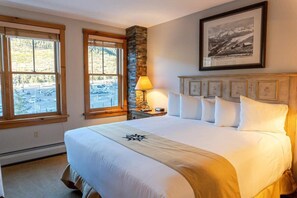 The master bedroom provides a comfortable space to rest with a king-size bed, attached bathroom, and bright windows offering views over the mountains.