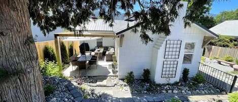 Front of the house with side patio complete with dining table, and sectional with gas fire pit.