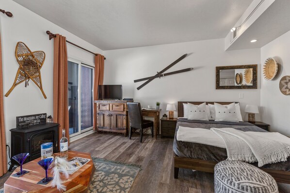 Living Room/Sleeping Space with plush sofa, queen bed (with twin rollaway), work desk, 32" smart tv, private deck access, and full bath access