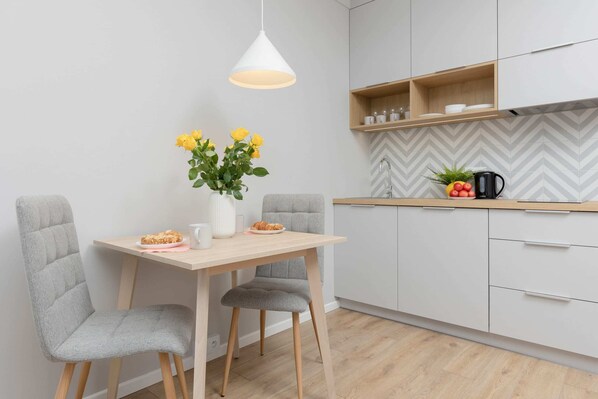A cozy dining space featuring a small wooden table with chairs, accompanied by a vase with fresh yellow flowers. 