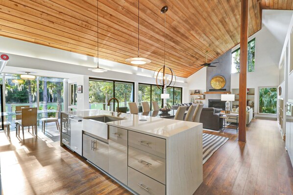 The kitchen island features stunning waterfall counter tops, an oversized farm sink, and stainless steel dish washer.