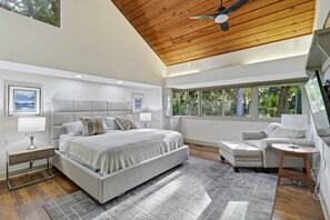 The spacious master bedroom has vaulted ceilings, a king sized bed, an over sized chaise, and a flat screen smart TV.