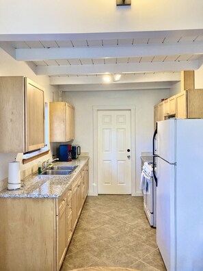 Well outfitted kitchen for cooking featuring wood cabinets and granite counters