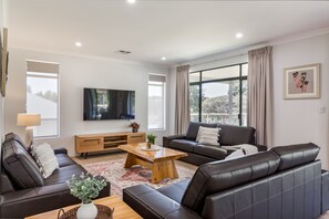 The inviting lounge area features plush leather sofas, a Smart TV, and plenty of space for everyone to unwind.