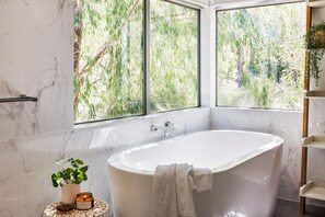 A freestanding bath in the primary suite offers leafy outlooks.