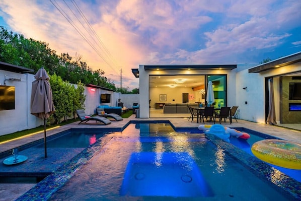 A fenced outdoor with pool, dining area, outdoor shower, patio set, fire pit, and BBQ & grill.