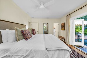 This elegant bedroom has a king-sized designer wood platform bed, teal-painted end tables, touch-control lamps, a private work desk, and French doors which lead out to the magnificent pool.