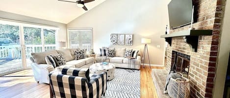 Open living room with ample seating, a fireplace, and a flat-screen television.