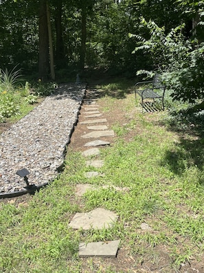 Garden area with bench and stone path to woods