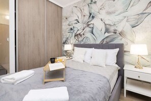 Bedroom with floral accent wall, cozy bedding, and wooden wardrobe.
