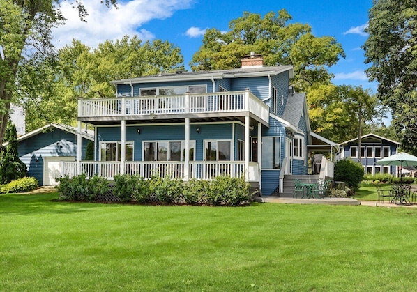 Back of home with two decks that look out to the water.