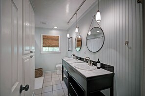 The hall bathroom with a double sink, shower/tub, and toilet. 