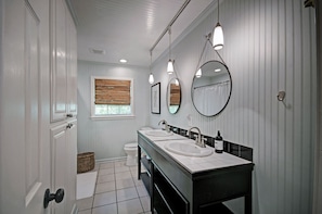 The hall bathroom with a double sink, shower/tub, and toilet. 