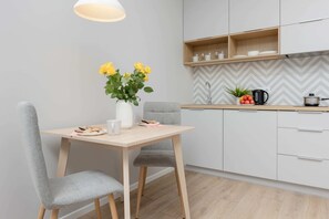 A cozy dining space featuring a small wooden table with chairs, accompanied by a vase with fresh yellow flowers.