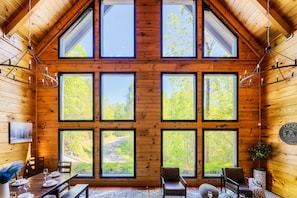 The great room boasts large windows with breathtaking tree-lined views. Soak in the natural light and peaceful scenery from the comfort of this inviting space