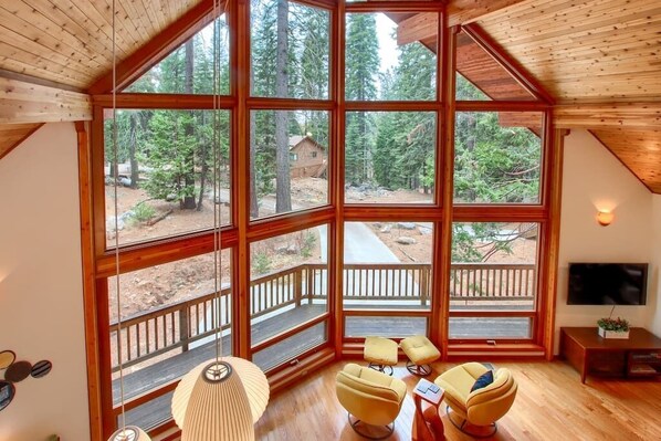 Cozy retreat with fireplace, tall ceilings & panoramic forest-view windows.