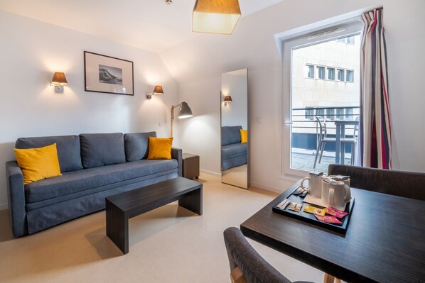 The cozy living area features a stylish sofa bed adorned with vibrant yellow cushions.