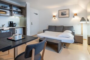 The living area transforms with the sofa bed pulled out, creating flexible sleeping arrangements ideal for small groups while maintaining a chic and functional aesthetic.