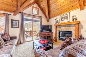 Living area with flat screen TV, gas fireplace, vaulted ceiling and access to the private balcony.