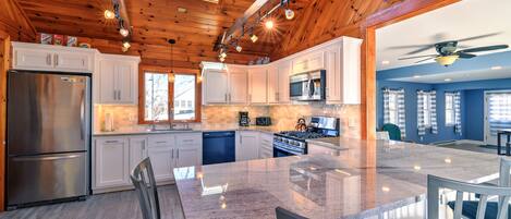 Beautiful updated kitchen with granite countertops, island that seats 6 guests and a wooden accent ceiling.