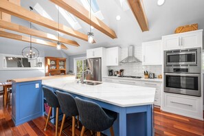 Large white updated kitchen with stainless steel appliances.