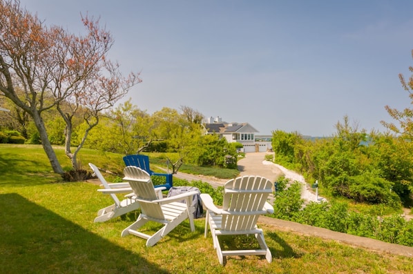 Front of the home with Adirondack chairs and firepit with ocean views.