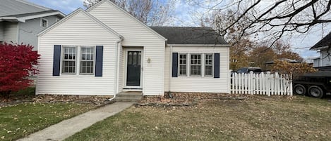 Front of the cottage with white picket fence on side yard. 