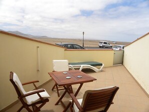 Patio with table, chairs and 2 sunbeds and mountain views