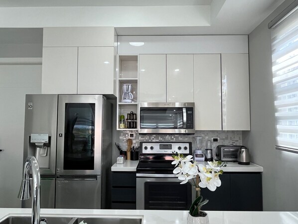 Kitchen with toaster oven, blender, magic bullet, coffee maker & kettle.