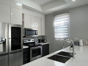 Kitchen with toaster oven, blender, magic bullet, coffee maker & kettle.