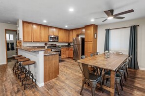 Kitchen with 4 bar stools, a dining table that seats 8, & stove w/oven.