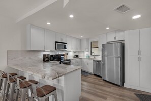 The Newly Remodeled White Kitchen features Beautiful Countertops and Stainless Steel Appliances.