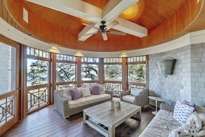 Sunlit sitting area surrounded by large windows, offering a serene spot to unwind with nature's beauty.