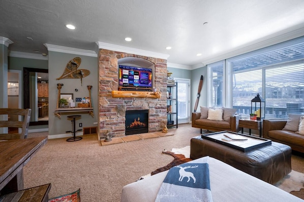 Experience the cozy living room, outfitted with plush seating, an expansive smart TV, and patio doors that frame the breathtaking mountain vistas.