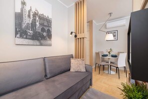 A living area with a grey sofa, wall art, and a wooden room divider, maintaining a modern and functional design.
