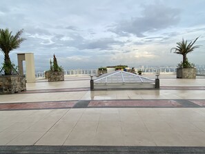 Roof deck overlooking Metro Manila skyline with lounges. 