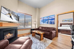 Living room: Queen pull-out bed and a Super Sleeper mattress topper, chair, electric fireplace, 48" smart TV
