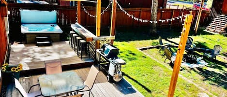 Large fenced in back yard with hot tub, patio, bbq grill, and fire pit