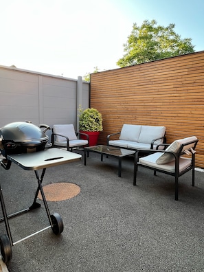 Cour privative avec salon de jardin, table, parasol et barbecue électrique 