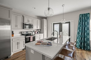 Fully stocked kitchen with quartz countertops and stainless steel appliances