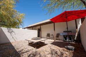Outdoor Patio: Enjoy sunshine, sizzle on the grill, and unwind under the vibrant red umbrella!