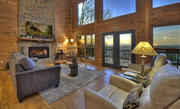 Spacious living room with a stone fireplace and large windows.