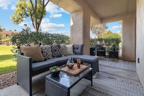 Private patio w/ L-shaped outdoor sofa, coffee table and two sitting chairs.