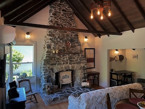 Restored stone fireplace with wood stove is the focal point of the main room.